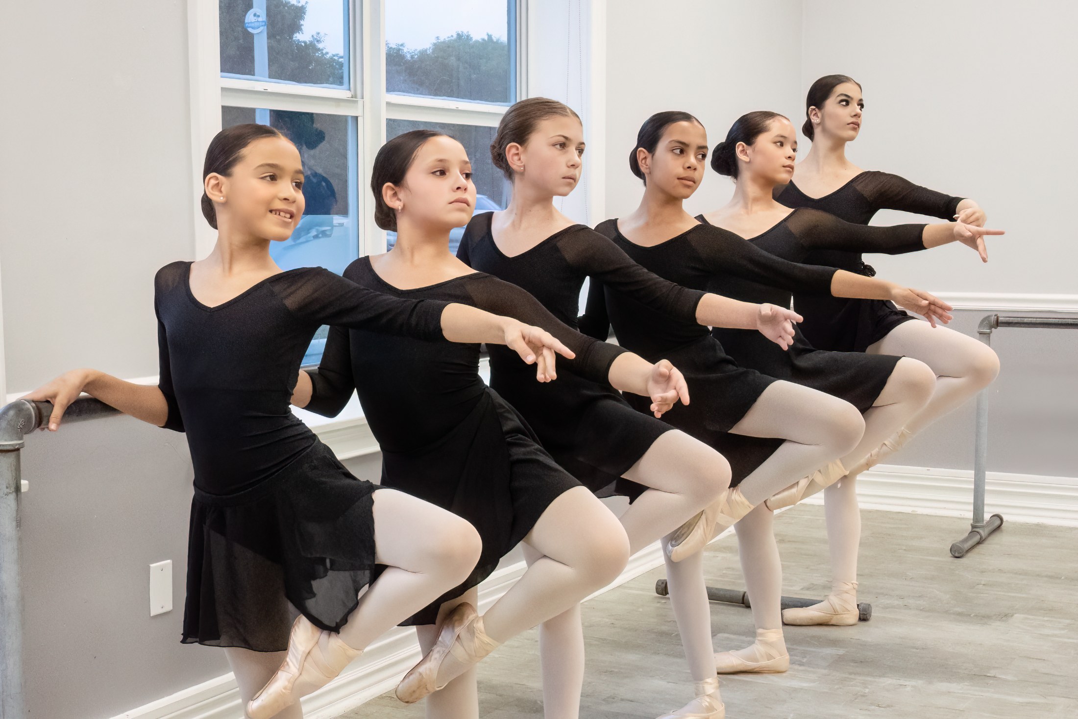 Dancers at the barre in retiré on pointe