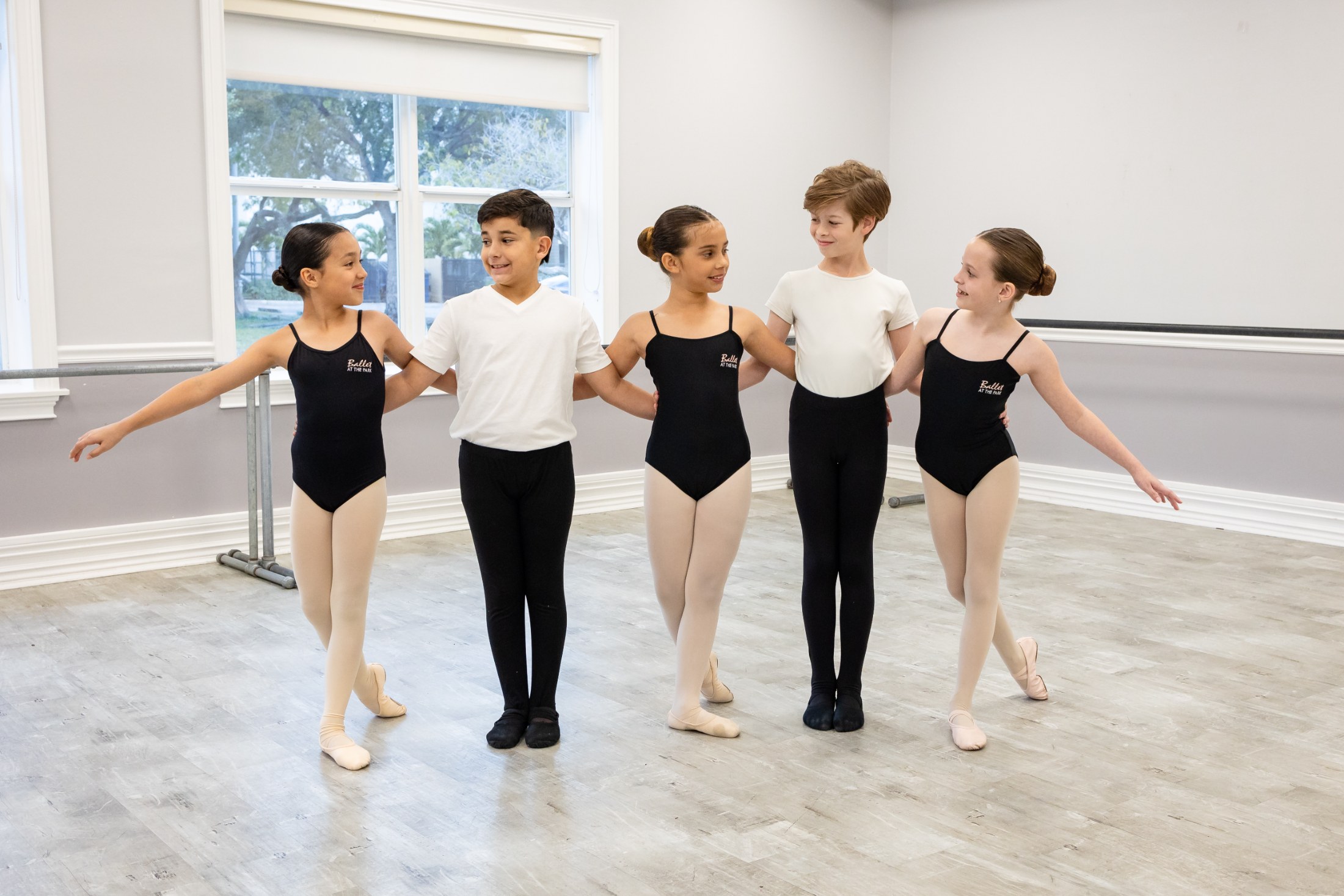 Five young dancers arm in arm in the studio
