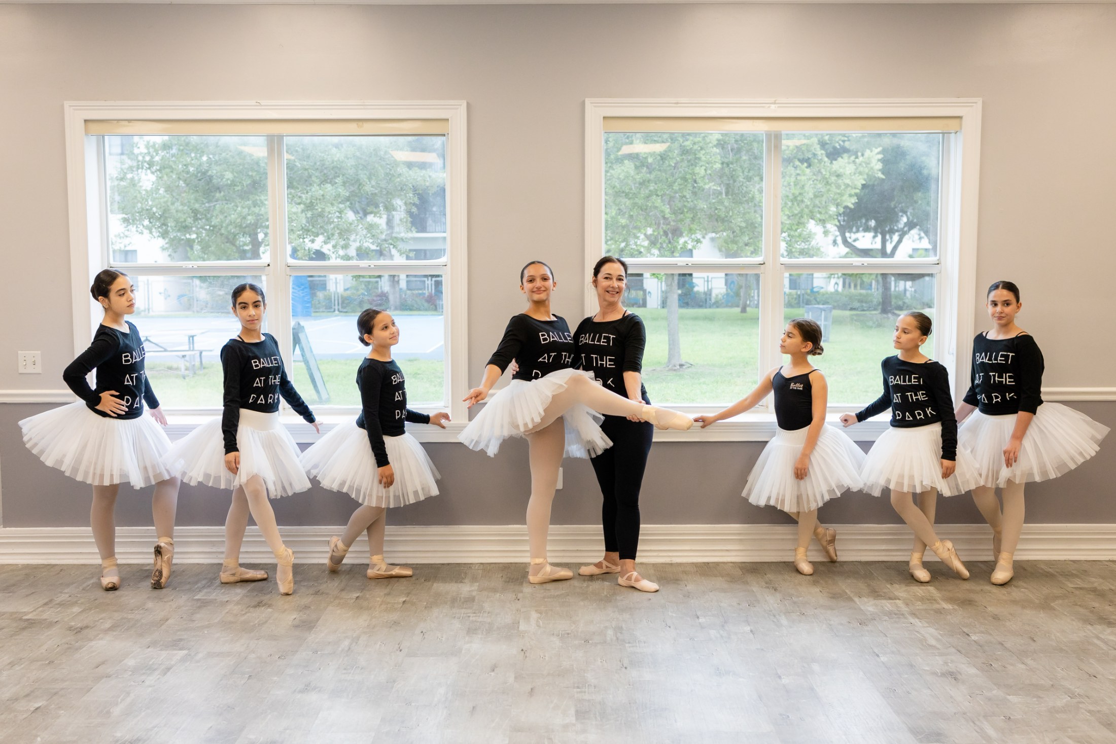 Dancers in tutus with their teacher at the studio windows