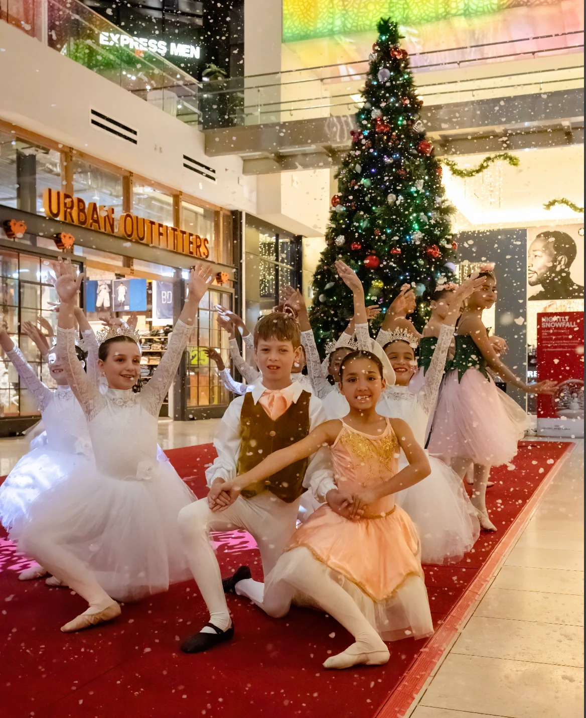 Ballet at the Park dancers in Nutcracker costumes under falling snow by a holiday tree